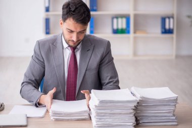 Young employee and too much work at workplace