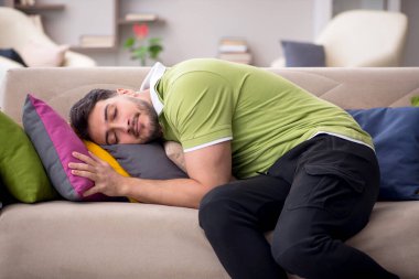 Evde bir sürü yastığı olan genç bir adam.