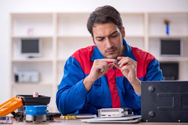 Atölyede bilgisayar tamir eden genç bir tamirci.