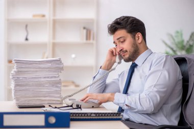 Young employee and too much work at workplace