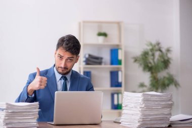 Young employee and too much work at workplace