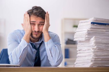 Young employee and too much work at workplace