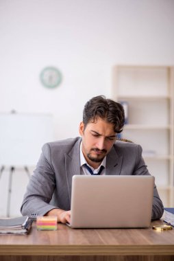 Genç işadamı işyerinde oturuyor.