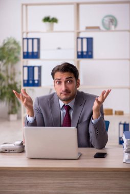 Genç işadamı işyerinde oturuyor.