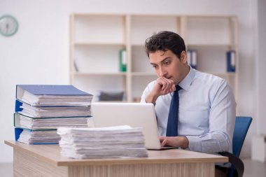 Genç işadamı ve işyerinde çok fazla iş var.