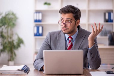 Genç işadamı işyerinde oturuyor.