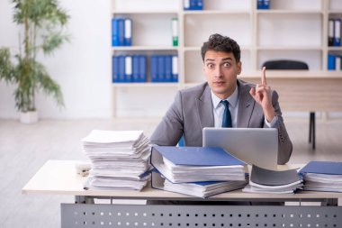 Young employee and too much work at workplace