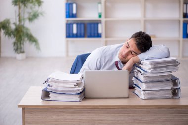 Young employee and too much work at workplace