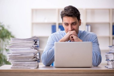 Young employee and too much work at workplace