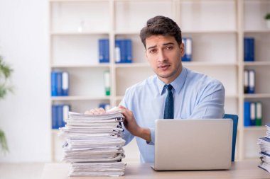 Young employee and too much work at workplace