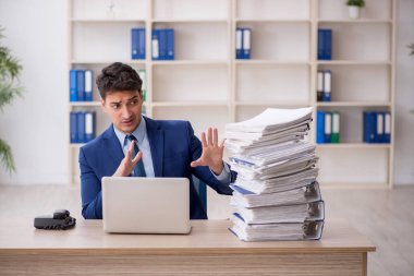 Young employee and too much work at workplace