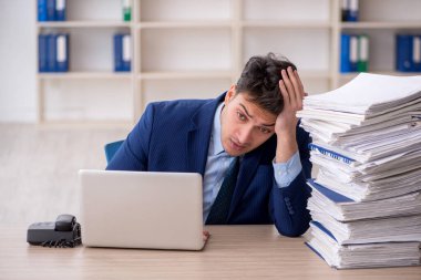 Young employee and too much work at workplace