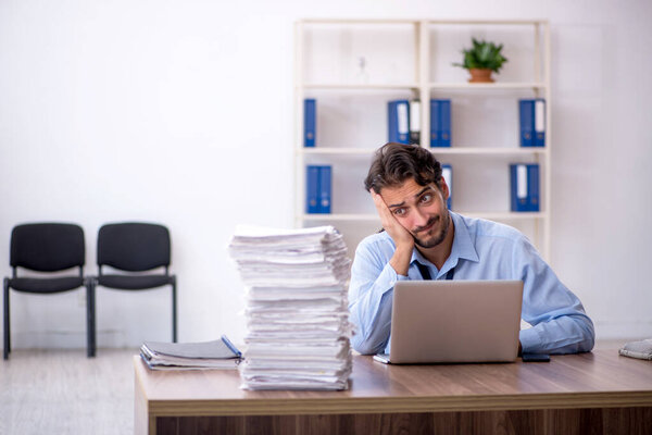 Young businessman employee and too much work in the office