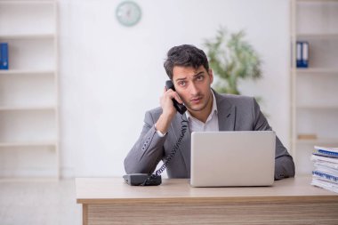 Young employee and too much work at workplace