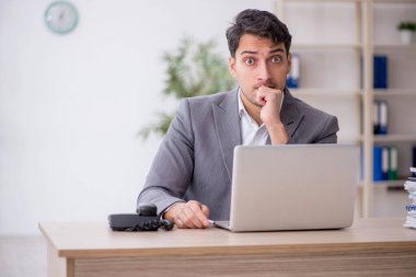 Young employee and too much work at workplace