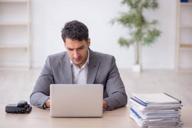 Young employee and too much work at workplace