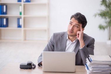 Young employee and too much work at workplace