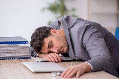 Young employee and too much work at workplace