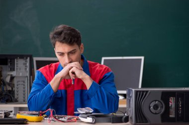 Sınıfta bilgisayar tamir eden genç bir tamirci.