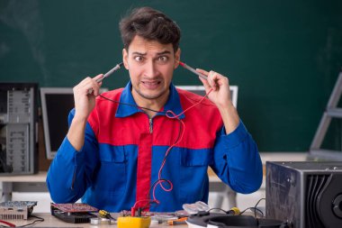 Sınıfta bilgisayar tamir eden genç bir tamirci.