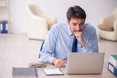 Genç işadamı işyerinde oturuyor.