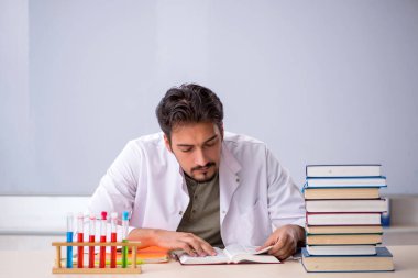 Genç kimyacı öğretmen beyaz tahtanın önünde.