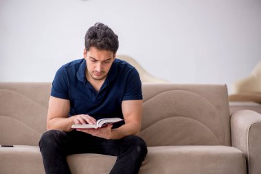 Evde kitap okuyan genç bir öğrenci.