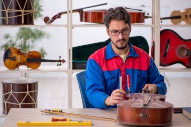 İçeride müzik aletlerini tamir eden genç bir adam.