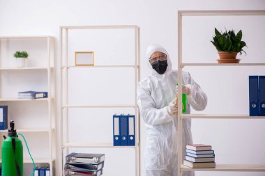 Young contractor disinfecting office during pandemic