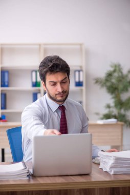 Young employee and too much work at workplace
