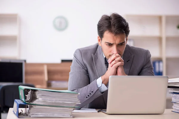 Young businessman employee unhappy with excessive work at workplace
