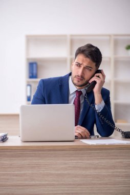 Genç işadamı işyerinde oturuyor.