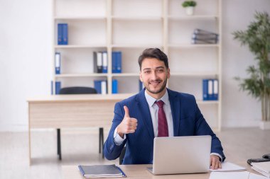 Genç işadamı işyerinde oturuyor.