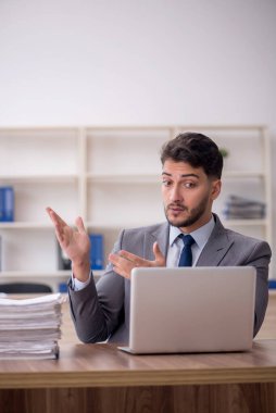 Young employee and too much work at workplace