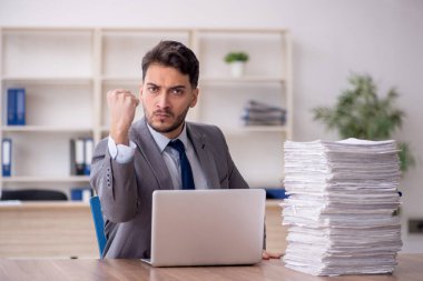 Young employee and too much work at workplace
