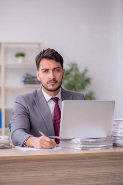 Young employee and too much work at workplace