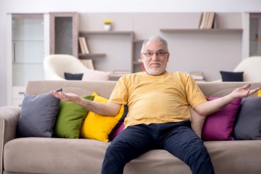 Evde bir sürü yastığı olan yaşlı bir adam.