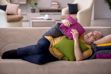 Evde bir sürü yastığı olan yaşlı bir adam.