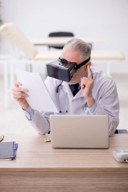 Old doctor wearing virtual glasses at the hospital