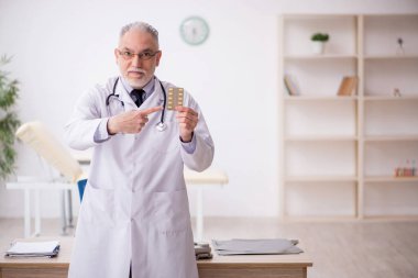 Old doctor suggesting pills at the hospital