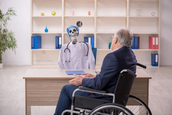 Old male patient in wheel-chair visiting devil doctor