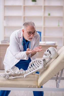 Old male doctor and skeleton patient at the hospital