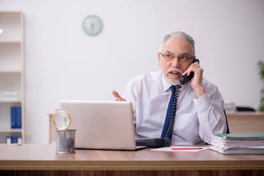 Old employee sitting at workplace