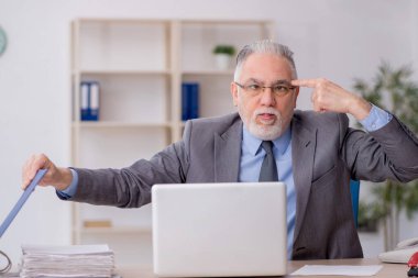 Old employee sitting at workplace