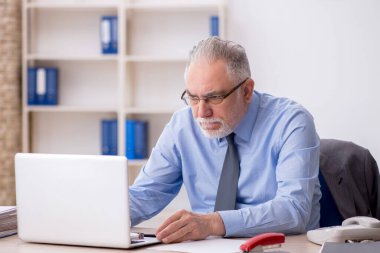 Old employee sitting at workplace