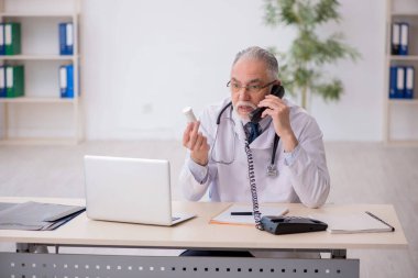 Old doctor suggesting pills at the hospital