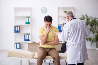 Genç hasta yaşlı doktoru ziyaret ediyor.