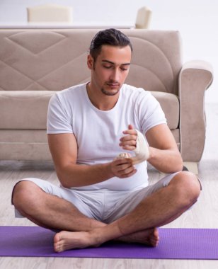 Evde egzersiz yapan eli yaralı adam.