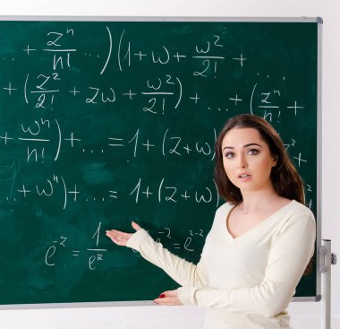Tahtanın önündeki genç bayan matematik öğretmeni.