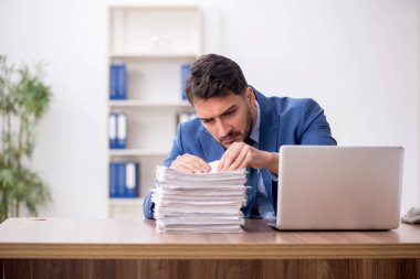 Young employee and too much work at workplace